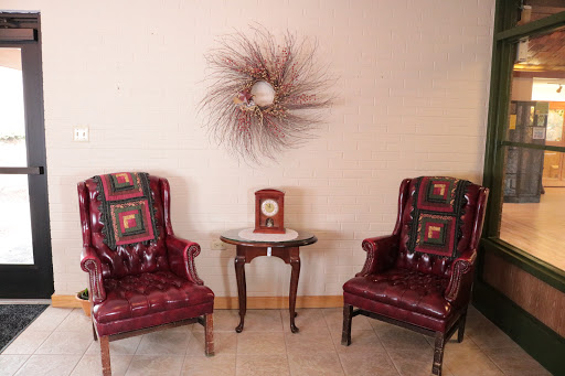 A cozy seating area featuring two vintage burgundy armchairs and a decorative wall piece.