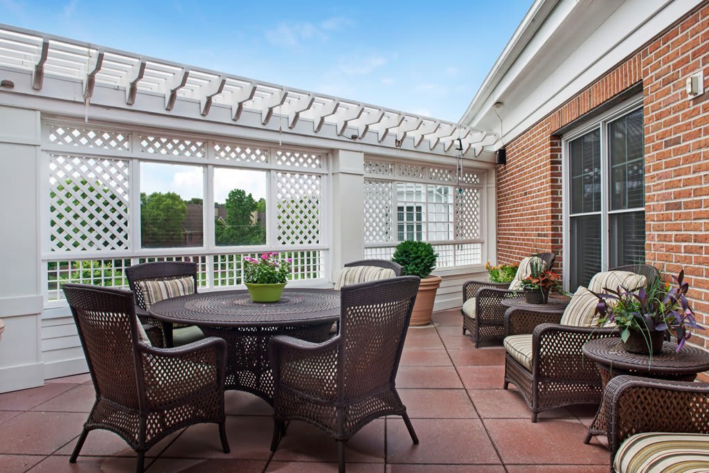 A cozy outdoor patio with a dining table, chairs, and a pergola.