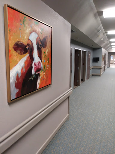 A colorful painting of a cow adorns the wall of a hospital hallway.