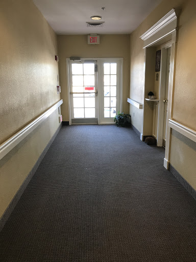 A quiet hallway leading to an exit door, featuring soft carpeting and a small plant.