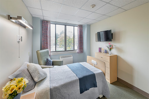 A cozy and well-lit bedroom featuring a comfortable bed, modern furniture, and a large window.