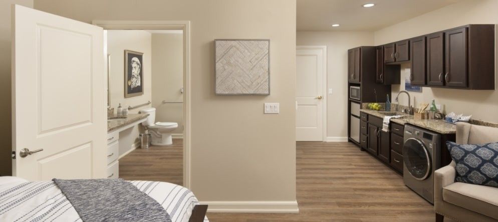 A modern interior view featuring a bedroom, bathroom, and kitchen area with hardwood flooring.