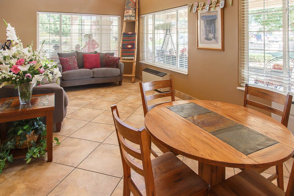 A cozy living and dining area featuring a comfortable sofa, wooden dining table with chairs, and large windows letting in natural light.