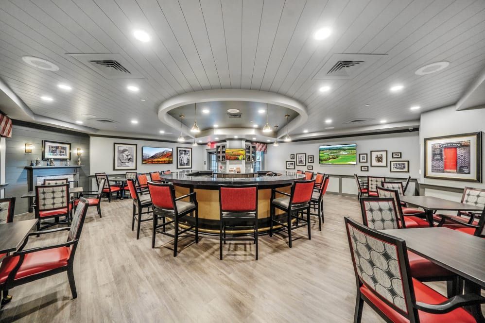 A modern bar interior featuring a circular seating arrangement surrounded by framed pictures and bright lighting.