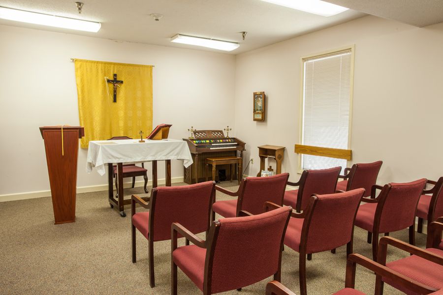 A small chapel with an altar, chairs, and a cross on the wall.