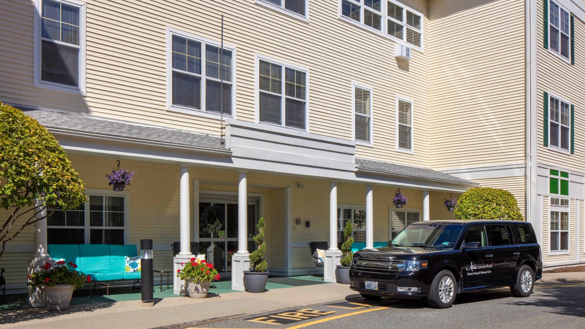 The entrance of a building with a porch area and a car parked in front.