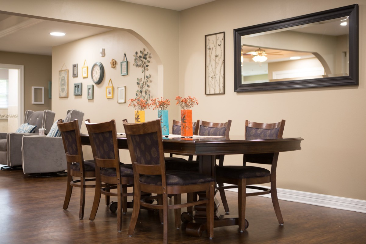 A cozy dining room setup with a wooden table and chairs, adorned with colorful vases and surrounded by wall decorations.