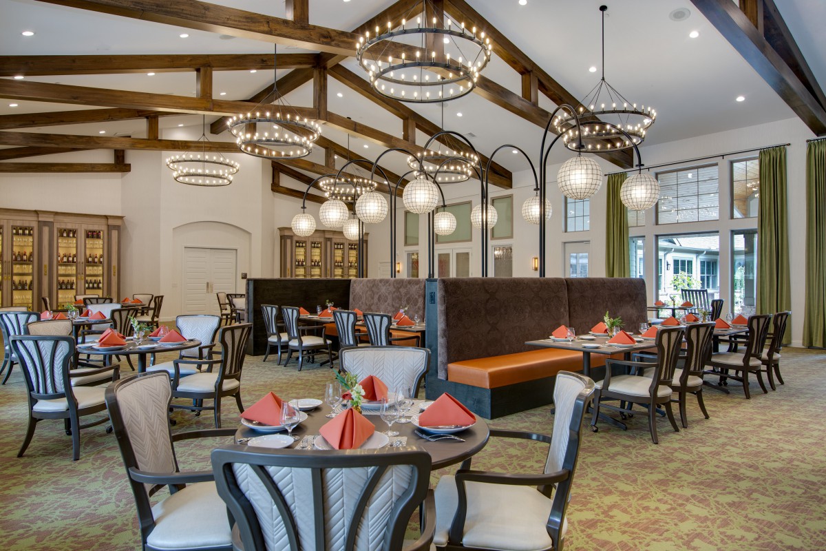 An elegant restaurant dining area with beautifully set tables and ornate chandeliers.