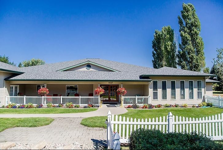 A single-story house with a manicured front yard and a white picket fence.