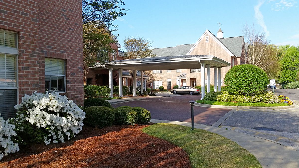 An exterior view of a building with a covered entrance and well-maintained landscaping.