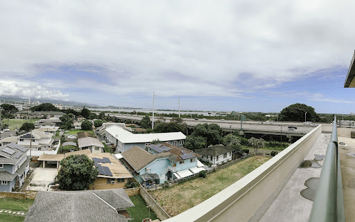 Aerial view of a suburban neighborhood with houses and a highway in the distance under a cloudy sky.