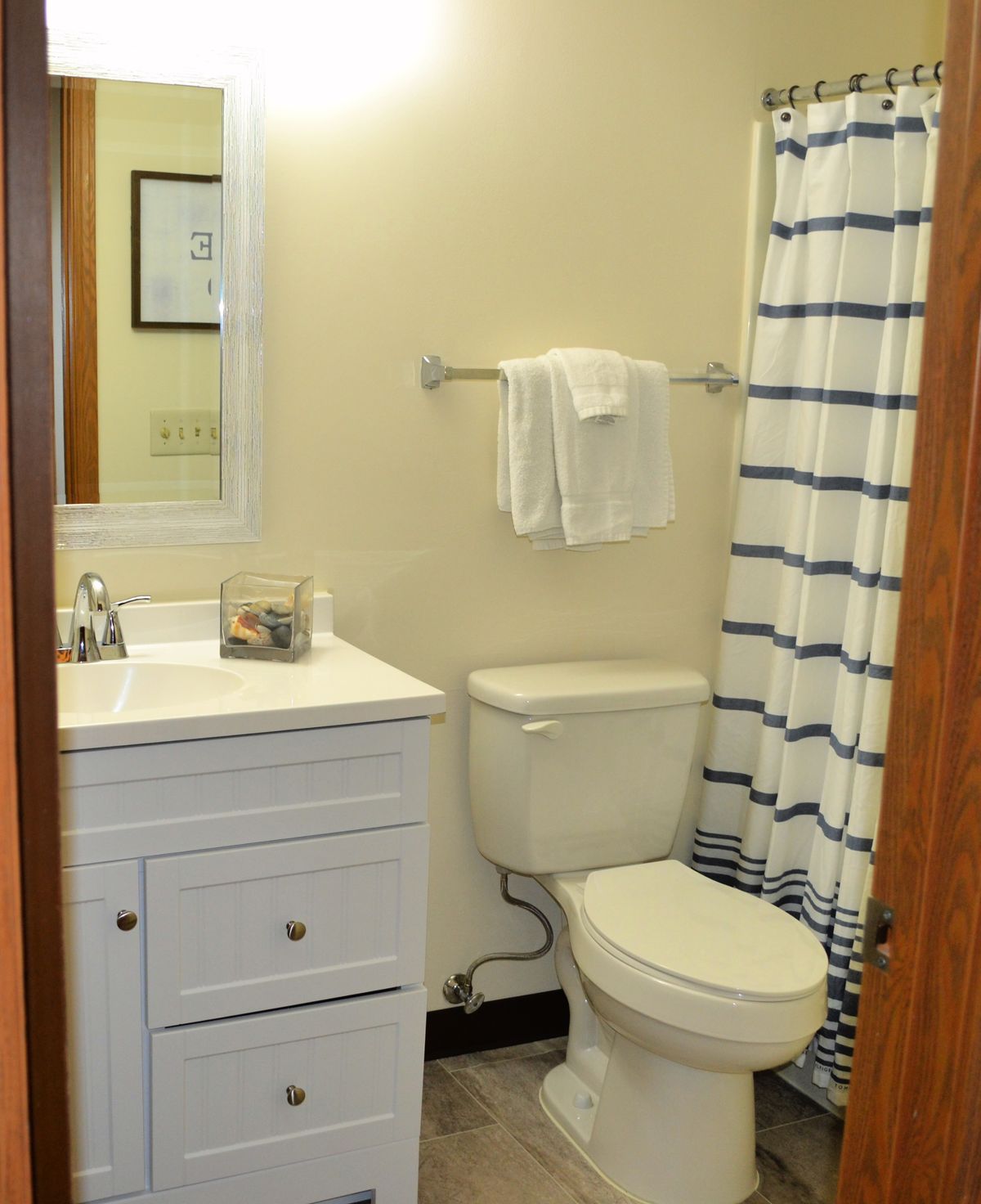 A small bathroom featuring a vanity with a sink, a toilet, and a striped shower curtain.