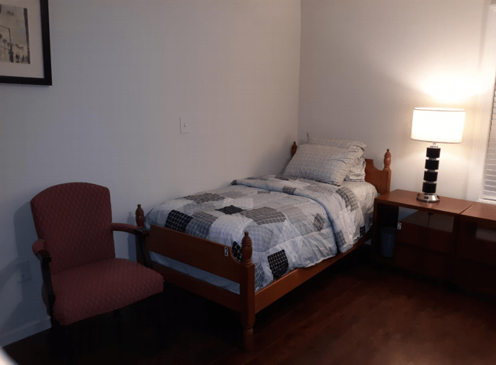 A cozy, minimalist bedroom with a single bed and a bedside lamp.