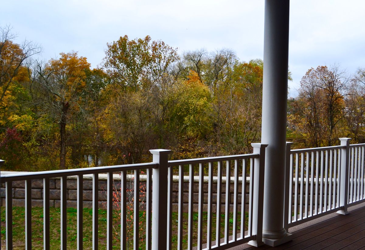 A scenic view from a balcony overlooking autumn trees.