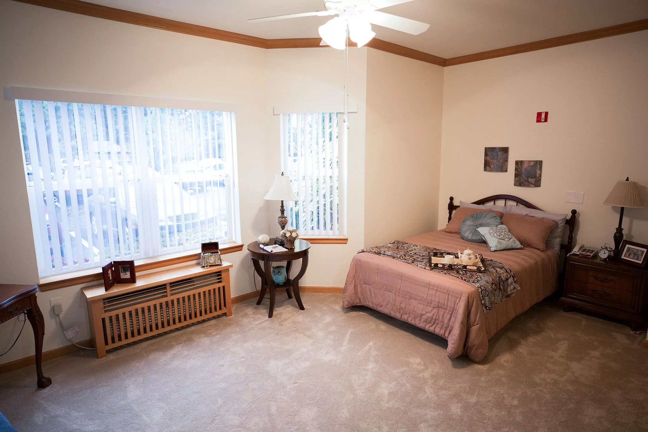 A cozy bedroom with a neatly made bed, large windows, and simple decor.
