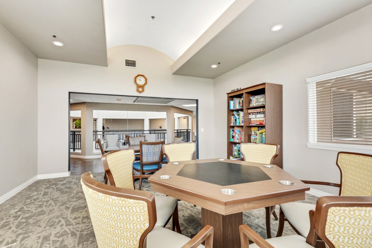 A modern library interior with a hexagonal table surrounded by chairs and a bookshelf filled with books.