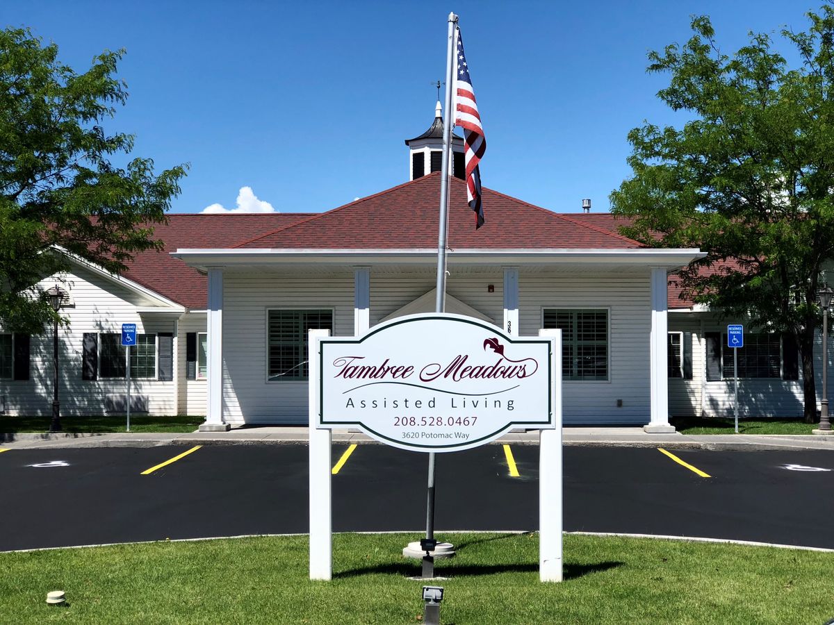 A building with a sign reading 'Carefree Meadows Assisted Living' and an American flag in front.