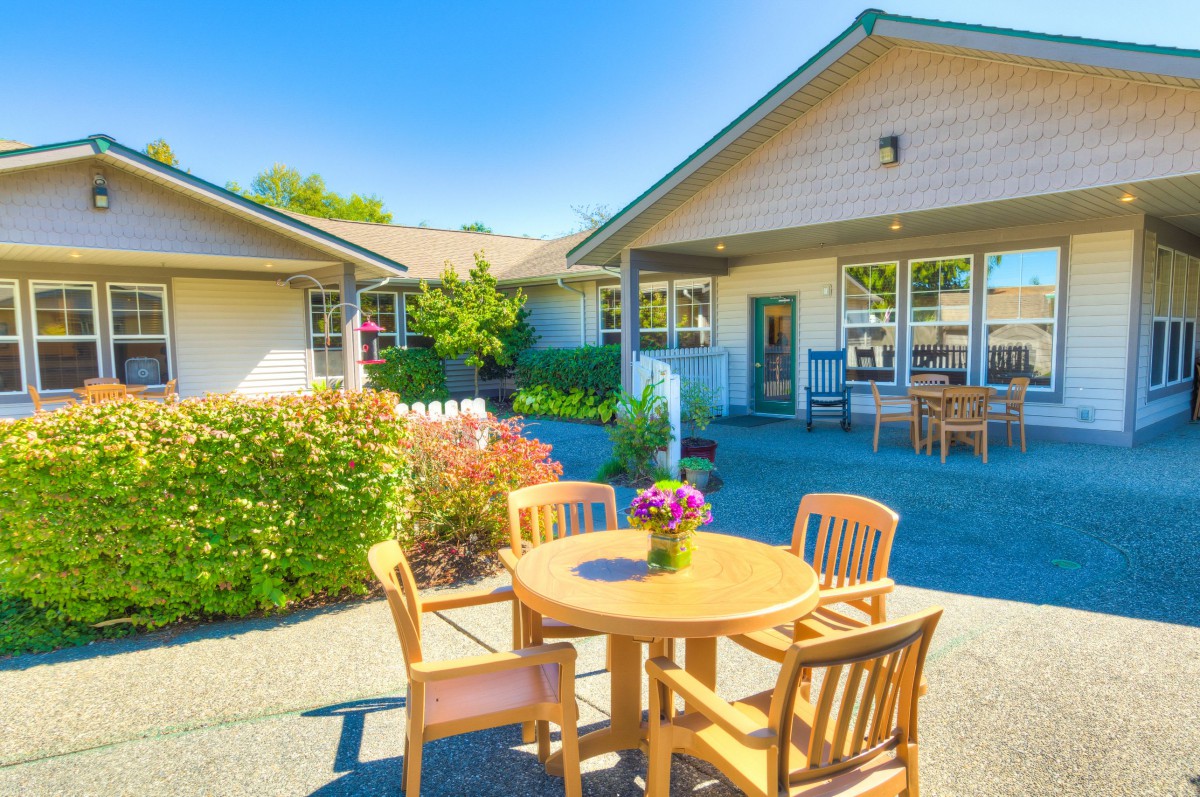A sunny outdoor patio area with wooden furniture and landscaped garden.