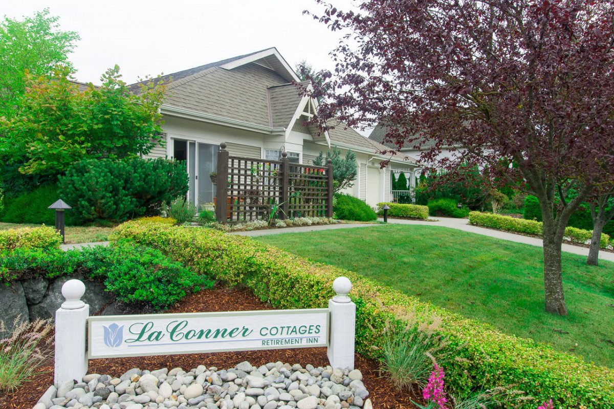 A well-maintained house with a lush garden and a sign reading 'La Conner'.
