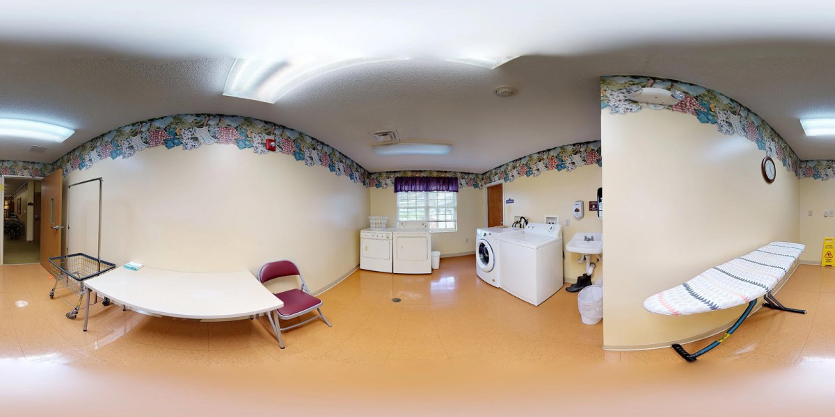A spacious laundry room with washing machines, a table, and chairs.