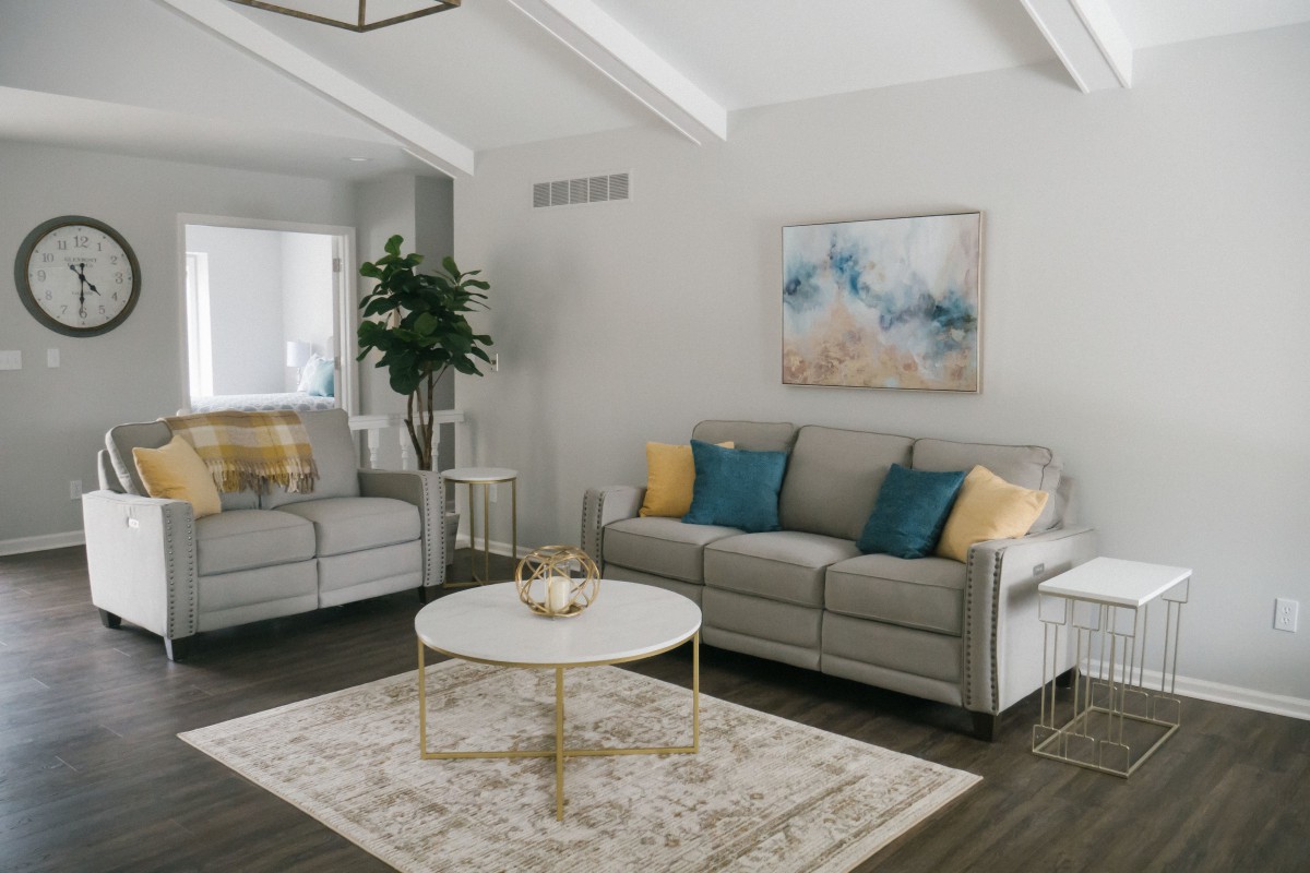 A modern and minimalist living room with grey sofas, a round coffee table, and abstract artwork.