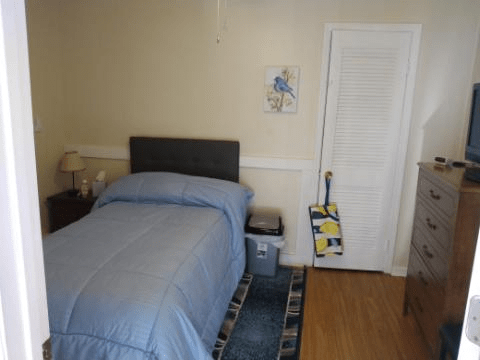 A cozy bedroom featuring a bed with blue bedding, a nightstand, and a closet door.