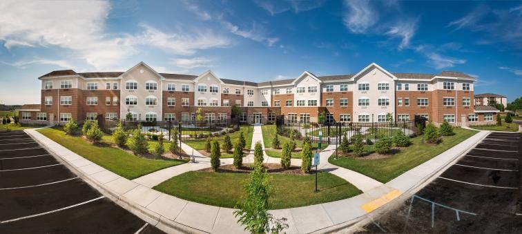 A modern apartment complex with well-maintained landscaping and clear pathways under a partly cloudy sky.