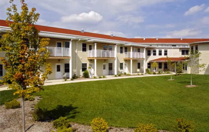 A two-story residential building with a well-maintained lawn and balconies.