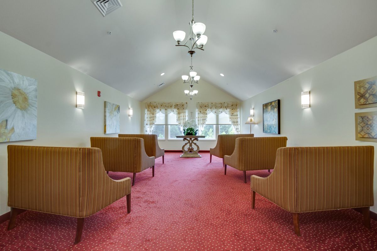 A neatly arranged lounge with chairs on a carpeted floor and elegant lighting.