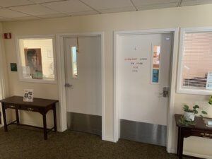 A hallway with two doors and a small table, featuring signs on the doors.