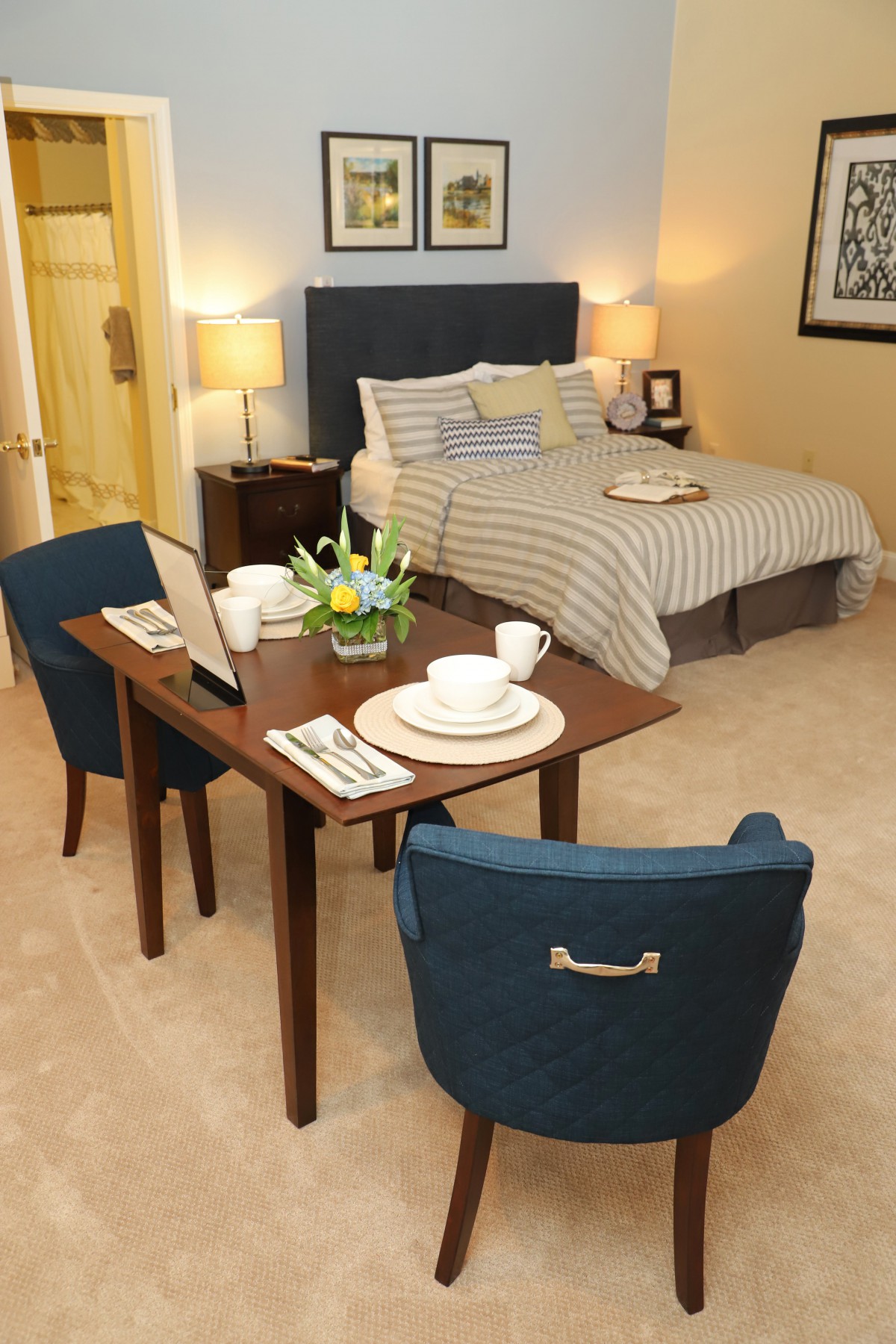 A cozy bedroom setup featuring a bed and a small dining table with two chairs.
