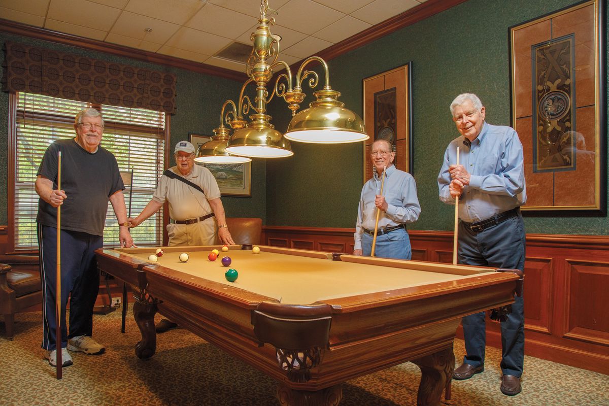 A group of people enjoying a game of billiards in a warmly lit room.