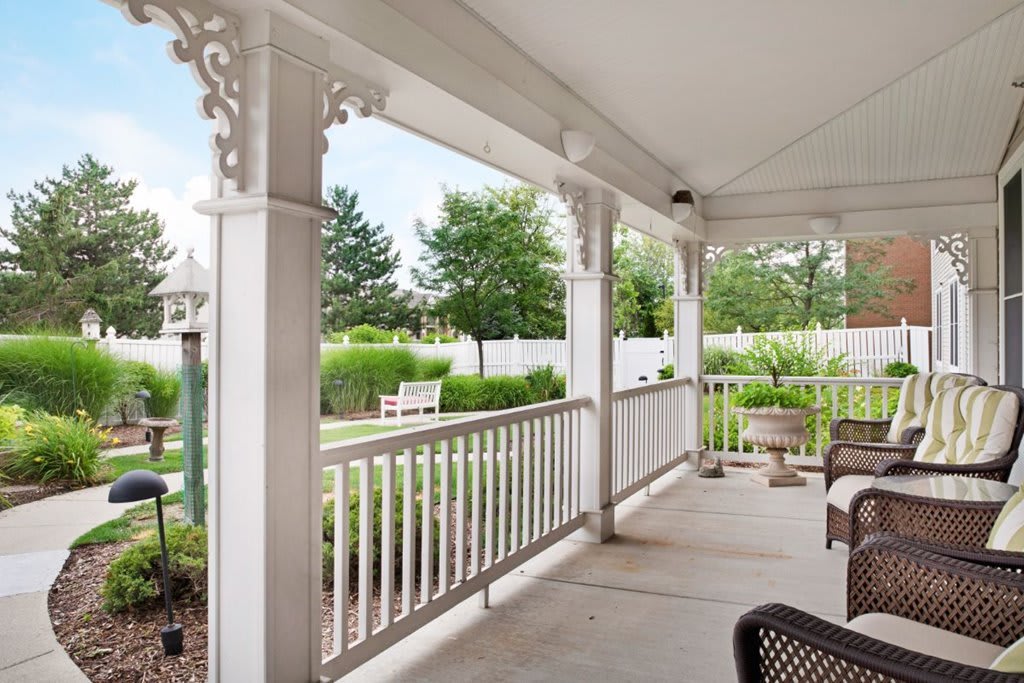 A peaceful porch overlooking a lush garden and white picket fence.