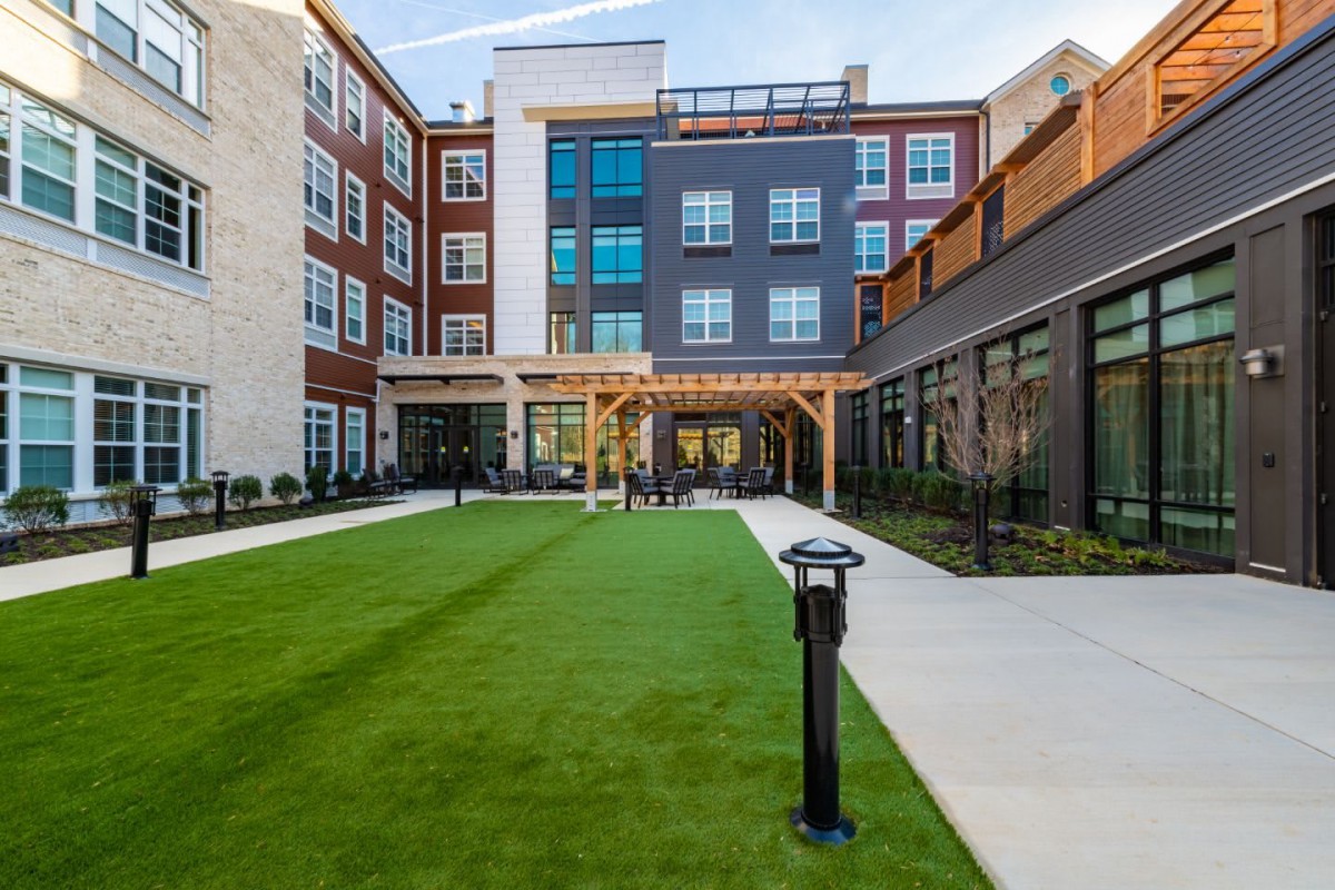 A modern residential building with a spacious courtyard featuring a well-maintained lawn.