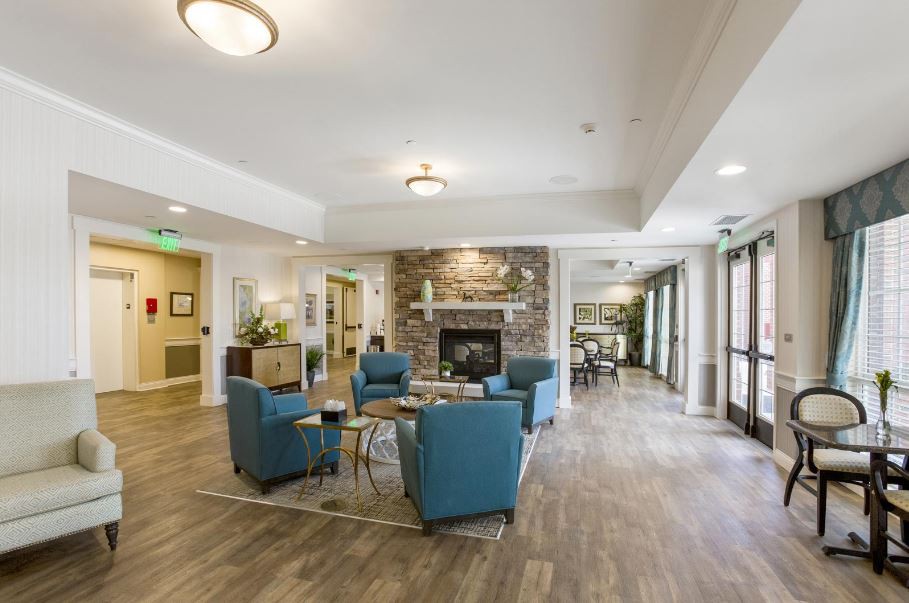 A modern lobby with a cozy seating area featuring blue chairs and a fireplace.