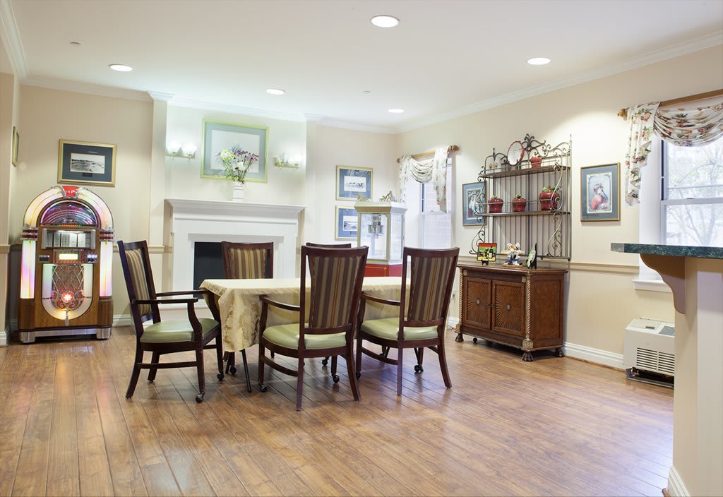 A cozy dining room with a wooden table and chairs, featuring a fireplace and decorative elements.