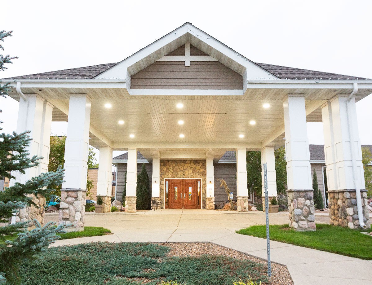 A welcoming building entrance with a covered walkway and landscaped surroundings.