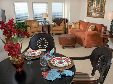 A cozy living room with a small dining setup, featuring comfortable seating and vibrant decorations.
