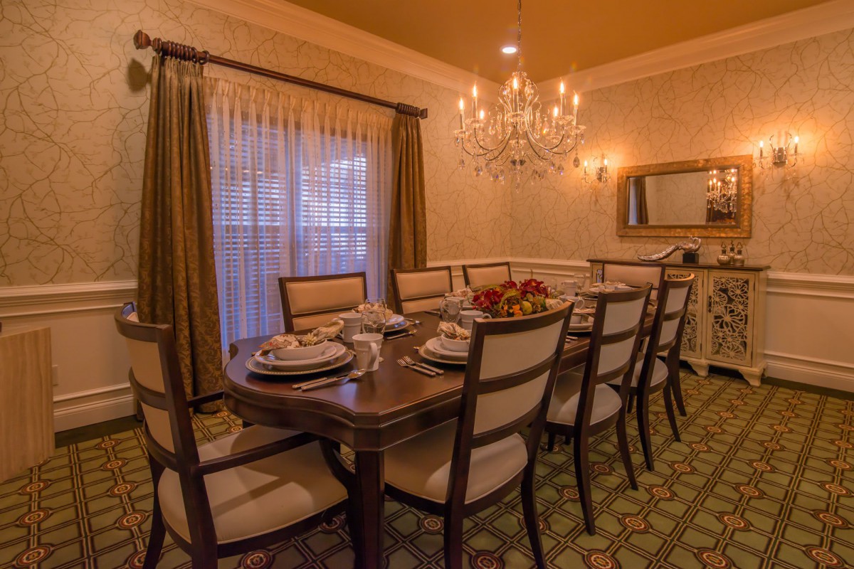 An elegantly set dining room table with a chandelier overhead and a warm, inviting ambiance.