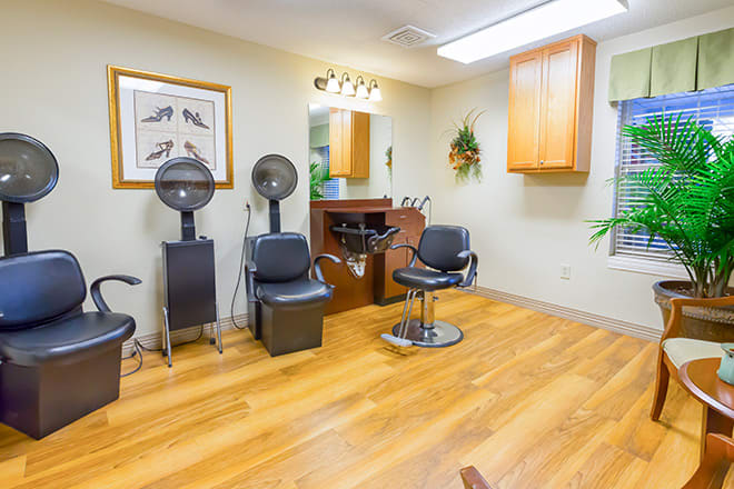 A cozy hair salon interior with styling chairs, dryers, and a mirror.