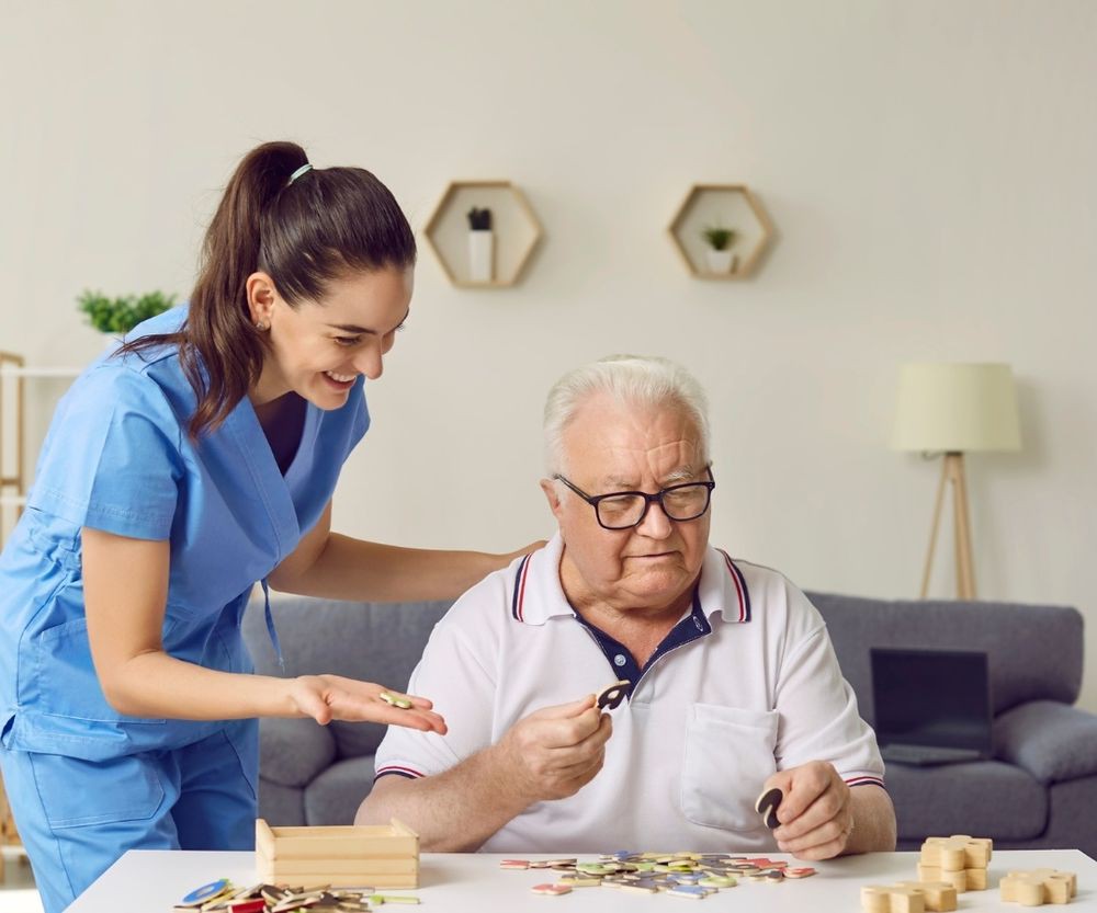 A caregiver helping an elderly man with a puzzle at home.