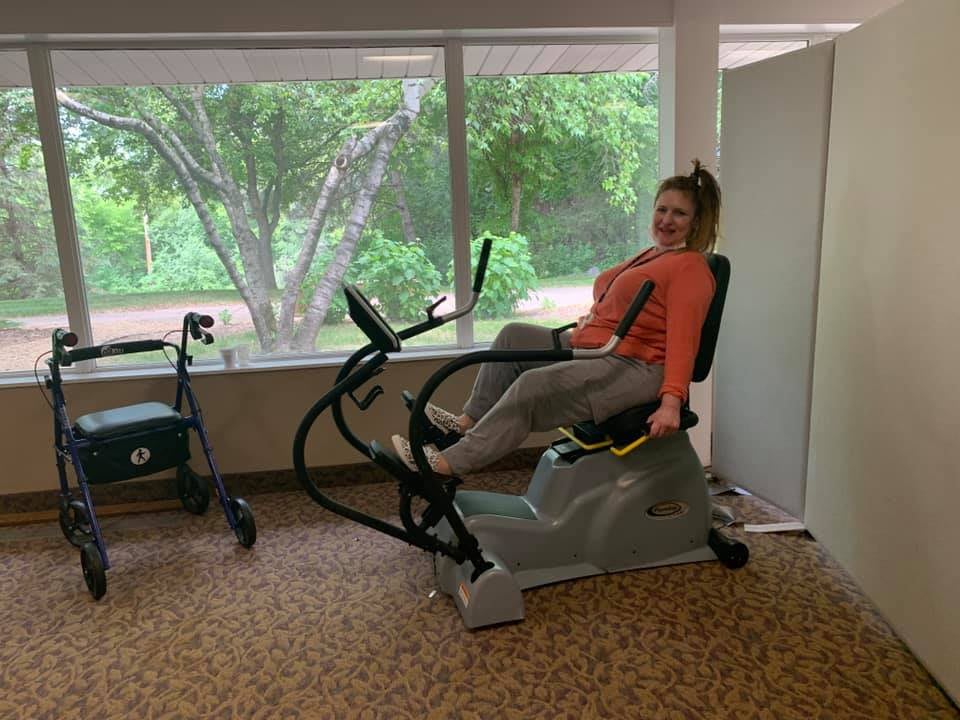 A person enjoying a workout session on a stationary bike in a brightly lit room with a scenic window view.
