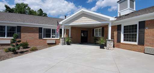 A welcoming entrance to a residential building, featuring decorative landscaping and an American flag.