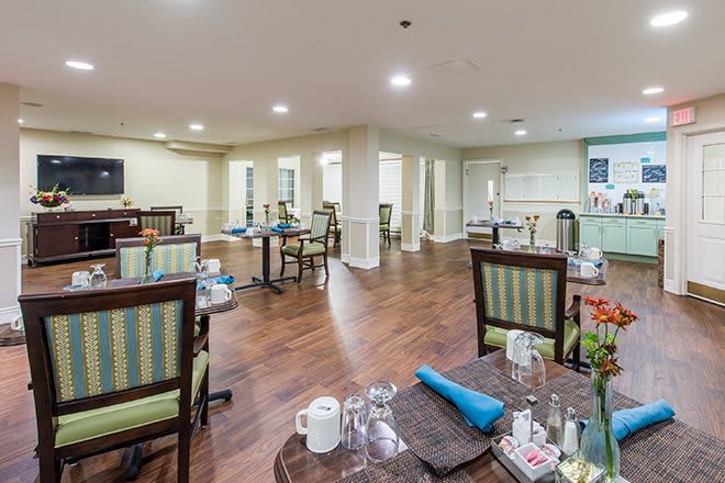 A well-lit dining area with wooden floors, neatly arranged tables and chairs.