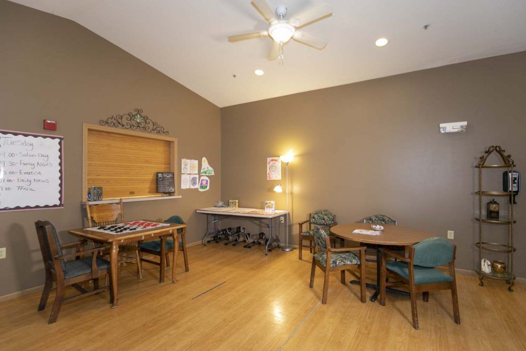 A room featuring tables and chairs, with a wooden floor and ceiling fan.