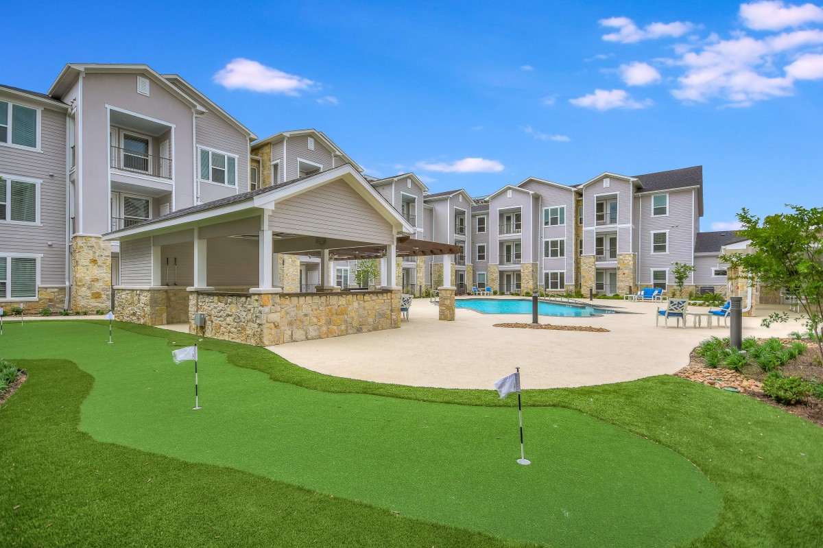 Modern apartment complex featuring a swimming pool and golf putting green.