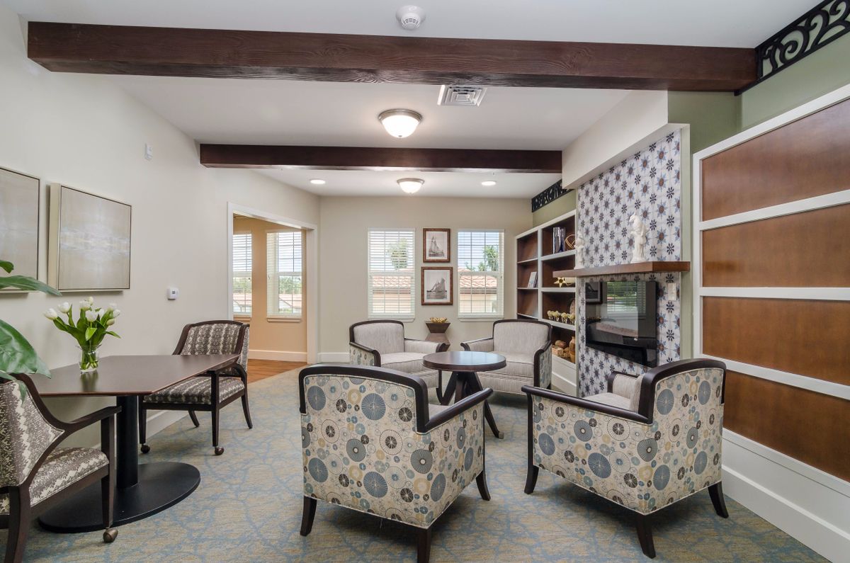 A cozy living room with comfortable seating, bookshelves, and decorative ceiling beams.
