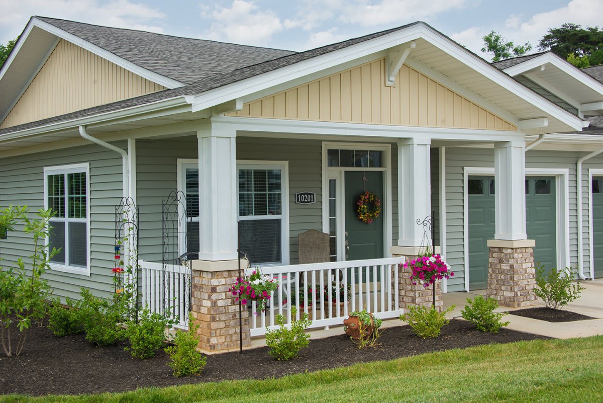 A charming cottage-style house with a front porch and well-maintained landscaping.