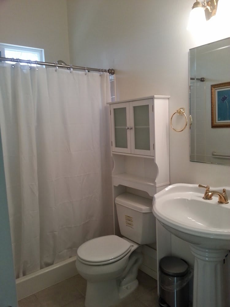 A small bathroom with a white shower curtain, sink, and toilet.