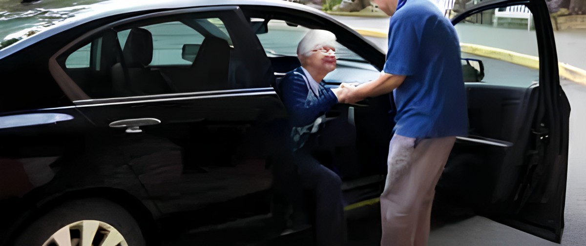 An elderly person being assisted out of a car.